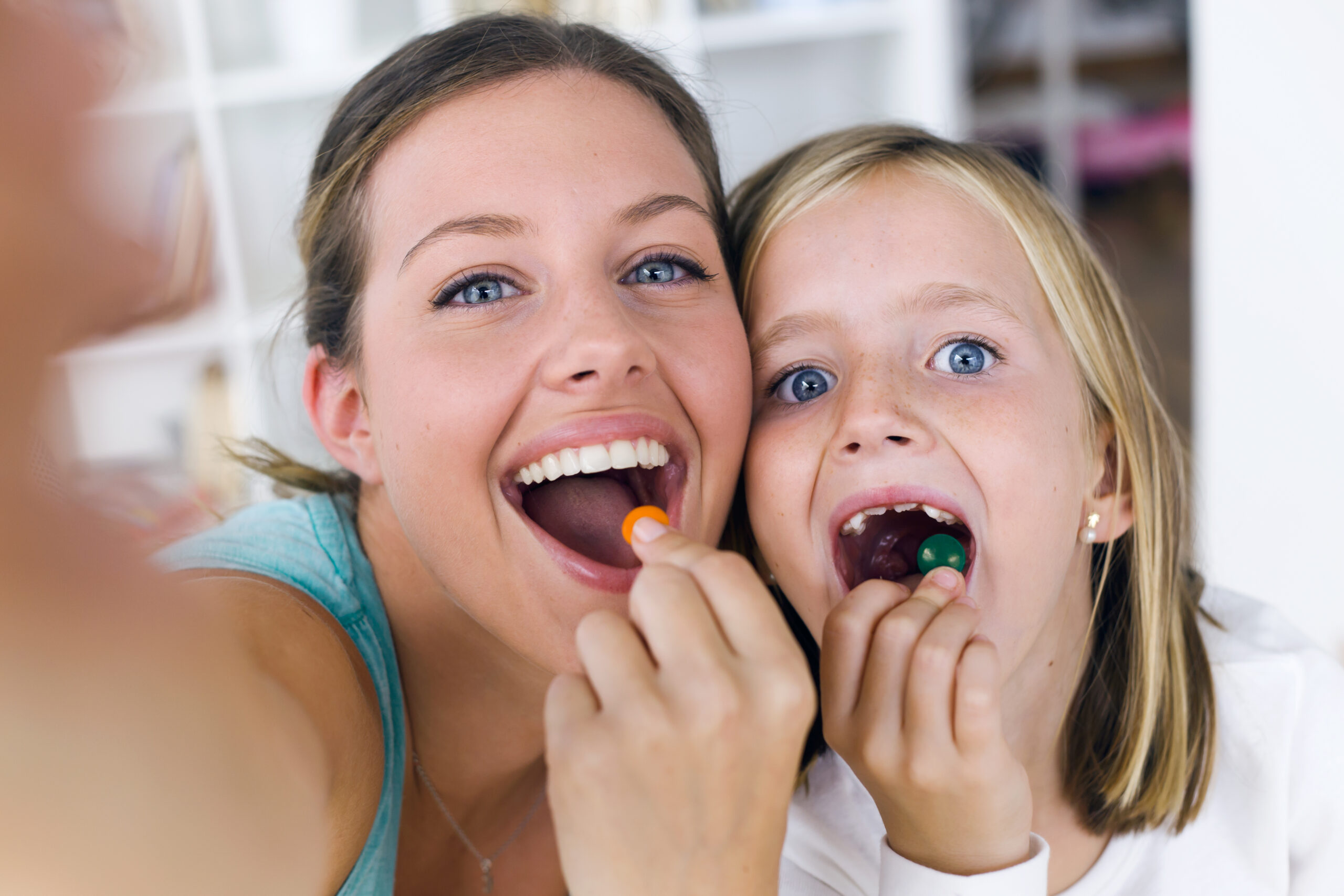 Portrait of young mother and daughter taking a selfie while eating sweets.