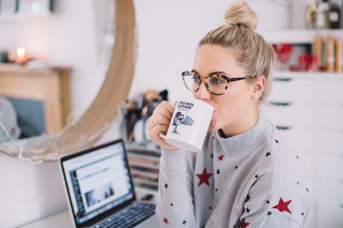 Female blogger drinking coffee at laptop